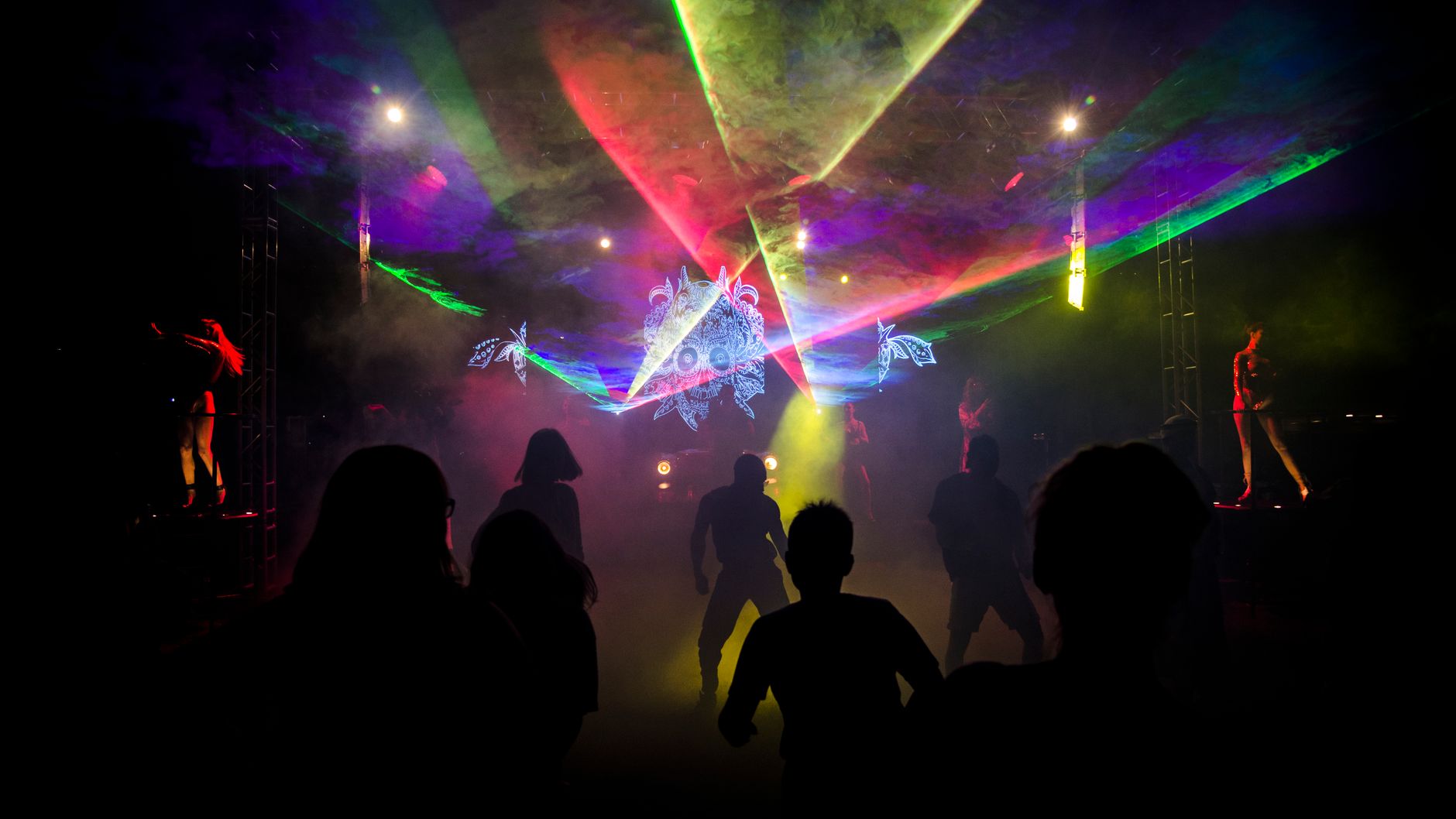 Dancers in silhouette under laser beams at a night event (illustrative stock photo).